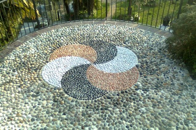 Girandola in ciotolini in tre colori:bianchi, neri, rossi su pavimento in ciotoli Ticino misti