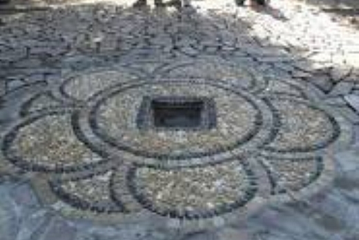 Fiore in ciotoli Ticino misti, con cornice in ciotolini color nero, contornato di cubetti 4/6 in porfido colori misti